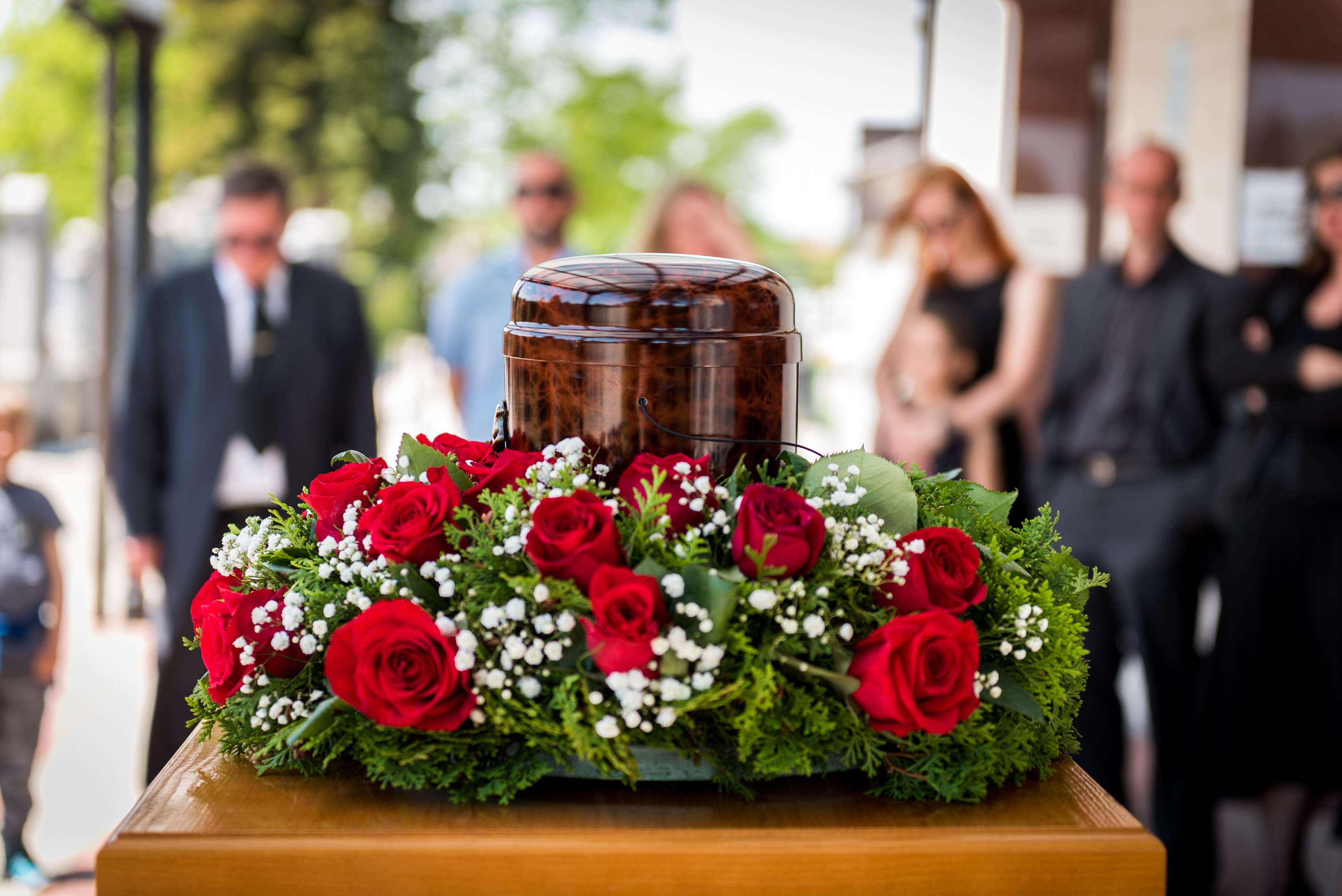 Funerary urn with ashes of dead and flowers at funeral. 