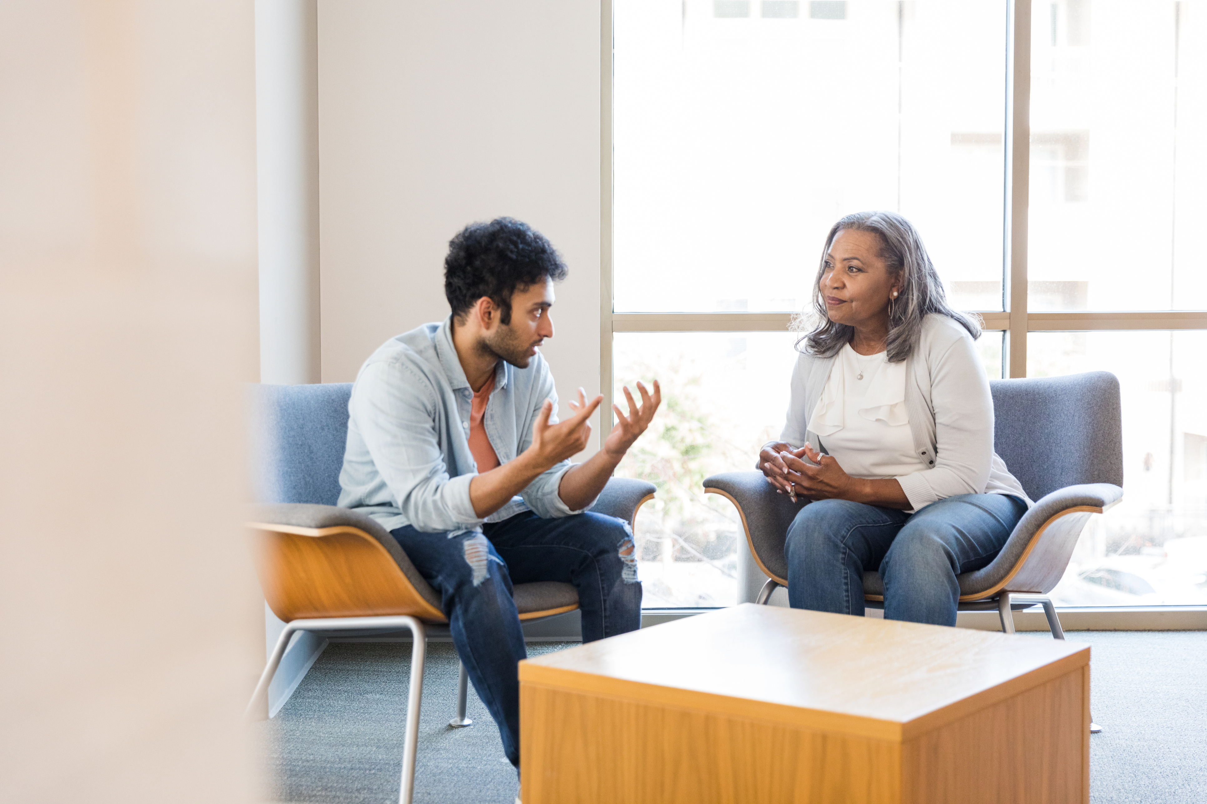 Young man gestures while sharing with female counselor